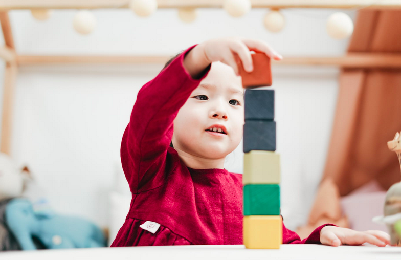 boy at a table playing and stacking his colorful blocks at home he is smiling